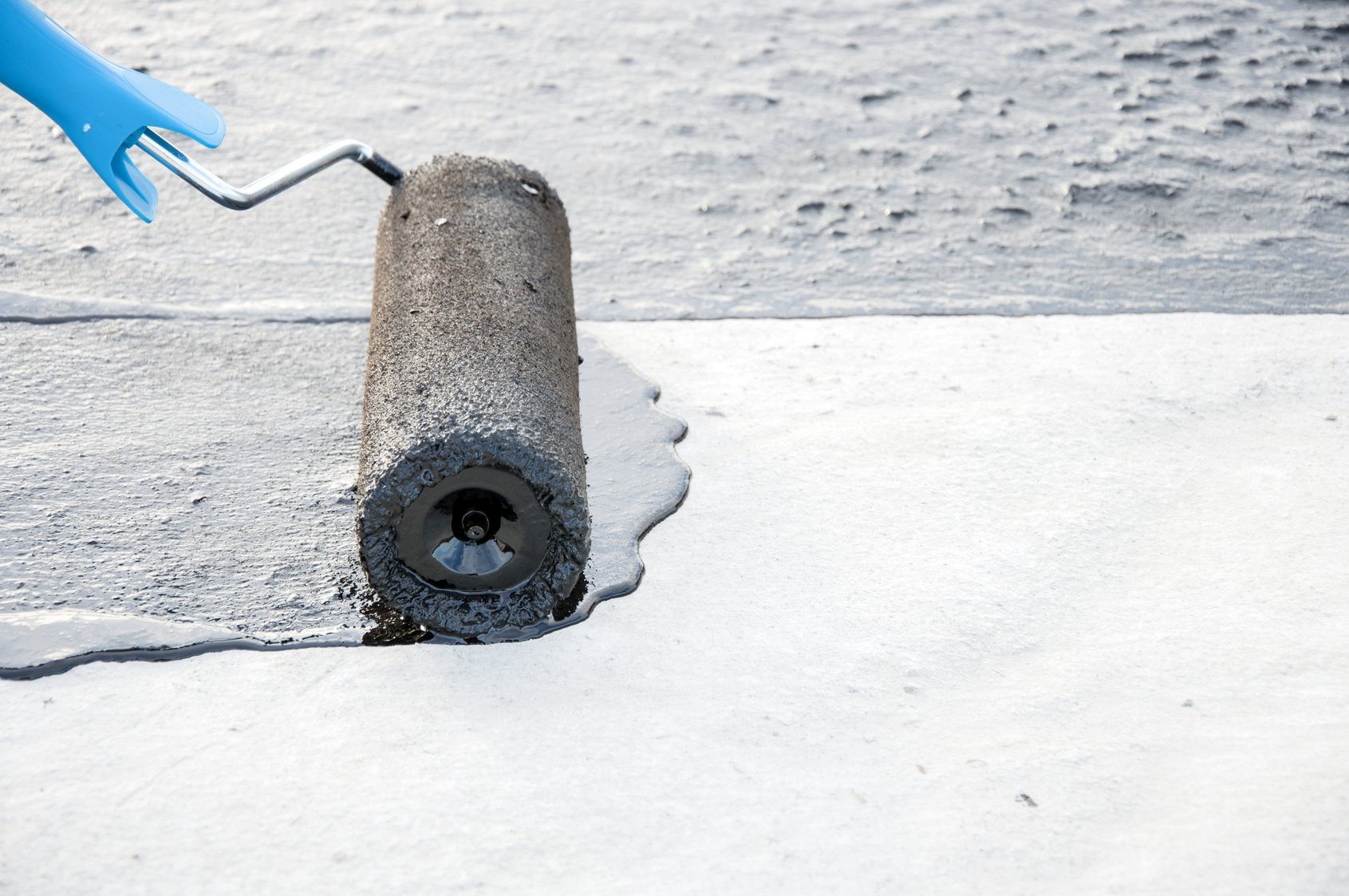 Roofer worker painting  bitumen praimer at concrete surface by t